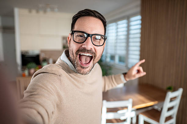istock Excited man pointing and vlogging a selfie at home 2247420675