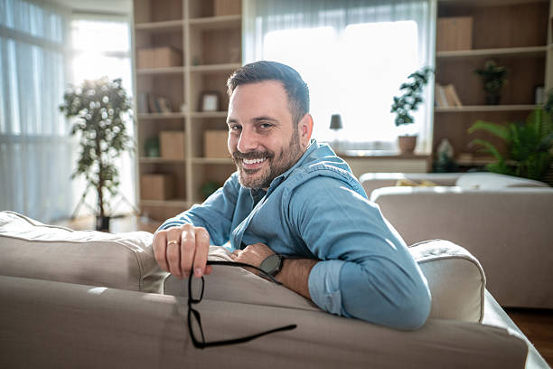 istock Happy man relaxing on living room sofa smiling at camera 2247423212
