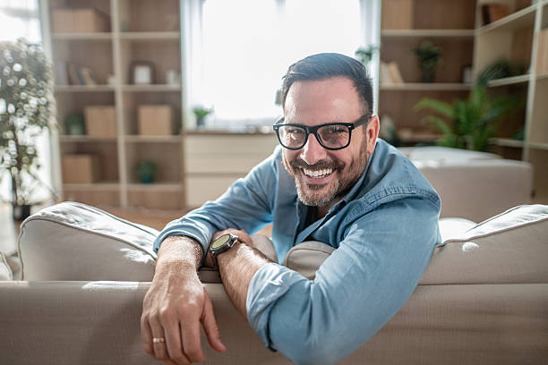 istock Man smiling on sofa in living room at home 2247423466