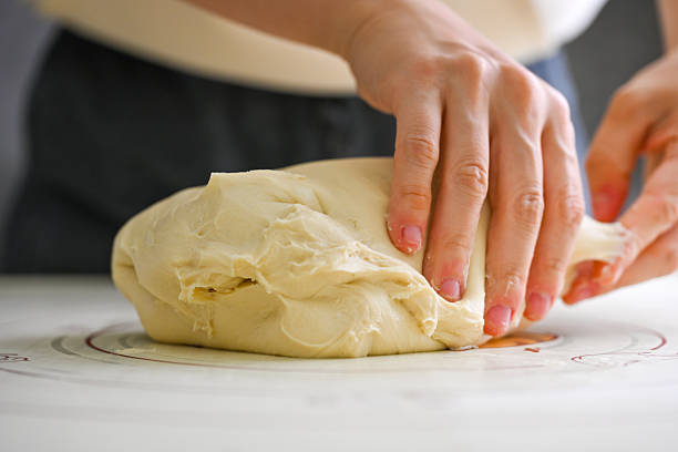 Hands kneading dough on a floured surface in a baking preparation process