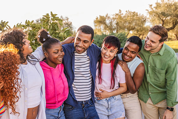 istock Diverse smiling young adults embracing outdoors together 2247425515