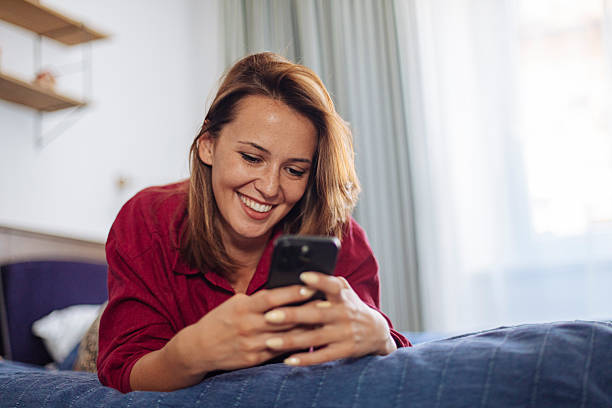 istock Smiling woman using smartphone at home 2247426207