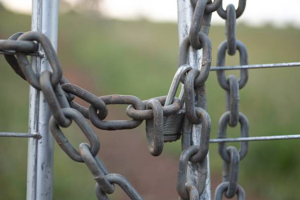 Chain wrapped around a metalic farm gate, locked with a deadlock