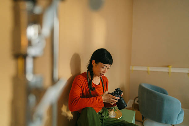 Photo of a Japanese woman holding a digital camera. She is going through the gallery on her camera.