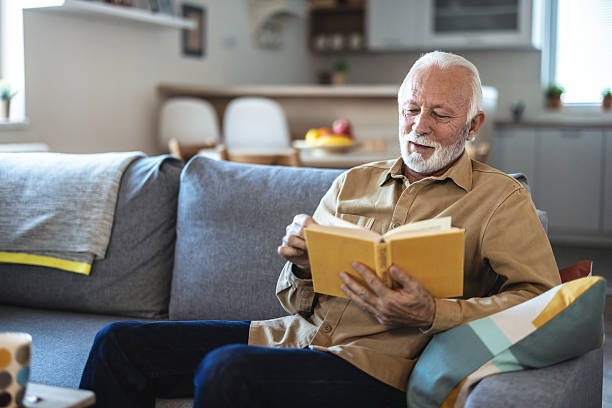 istock Senior man, reading book and relax on sofa with study, literature and information in lounge at apartment. Elderly person, novel and knowledge on couch with language for storytelling in living room. 2247430079