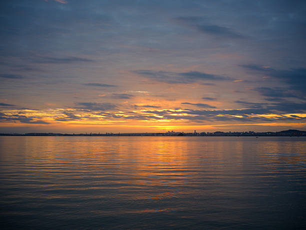 A Serene Sea Surface at Sunset with Golden Reflections and a Dramatic Sky