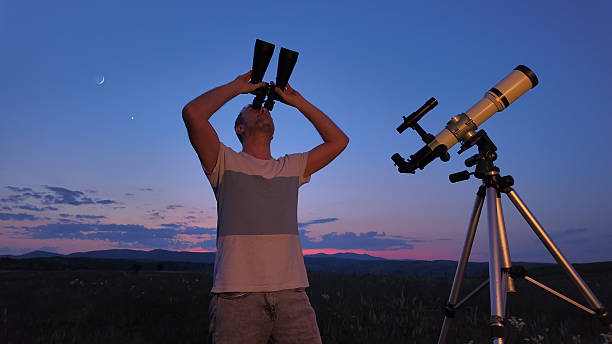 istock Amateur astronomer using telescope and binoculars for watching stars, Moon, planets and other celestial objects from a countryside field in nature. 2247436442