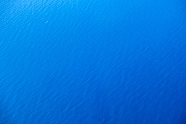 Minimalist aerial view of tranquil blue water surface with gentle ripples in bright daylight