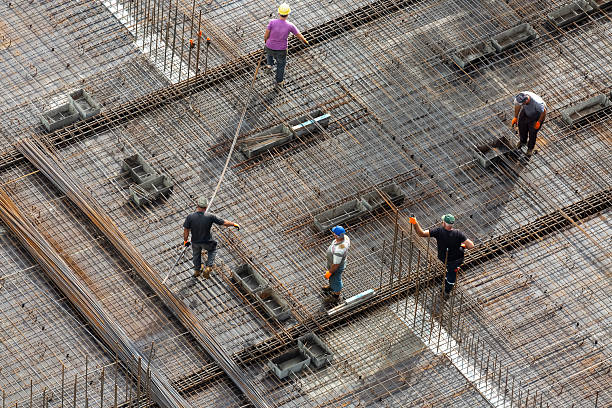 A construction crew is laying a metal mesh for pouring concrete to create a monolithic overlap between the floors of  the residential building \