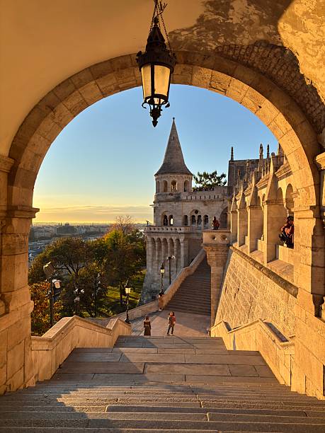 Tourists stroll through the elaborate Fisherman's Bastion in Budapest, admiring the unique towers and enjoying the beautiful evening light.