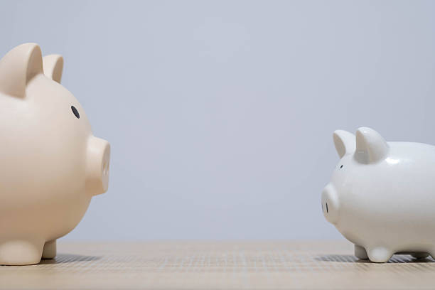 istock Two piggy banks facing each other on a wooden surface symbolize financial comparison, budgeting choices, saving strategies, and money management in a clean, minimal and modern financial concept. 2247451846