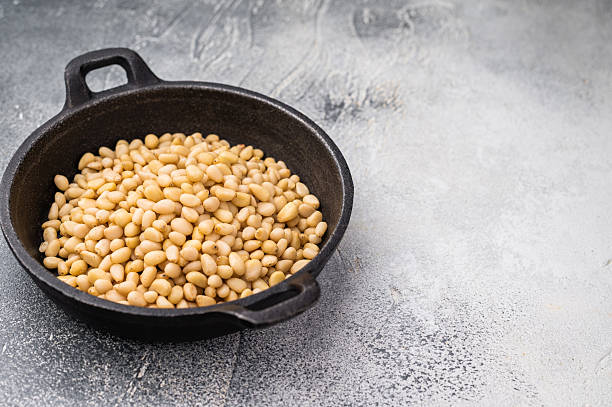 istock Raw pine nuts arranged in a small cast iron dish on a slate plate over a light textured surface creating a clean contrast for recipe and food visuals 2247452943