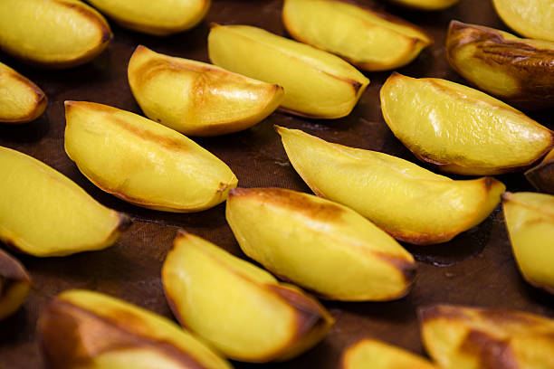 Golden roasted potato wedges sit on a baking tray, showcasing their crispy edges and tender inside. Ideal for family dinners and casual gatherings as a tasty side dish.