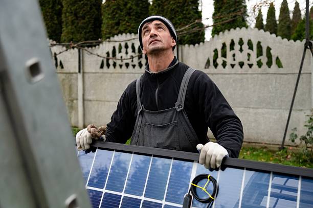 istock Man installs solar panels in a garden during daylight hours while wearing protective gloves 2247457612