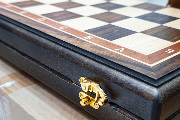 istock Luxurious wooden chessboard with gold latch and smooth finish displayed on a table with cardboard background during a sunny afternoon 2247458658