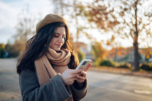 istock Cheerful Woman Checking Messages Outdoors on a Crisp Autumn Day 2247459091