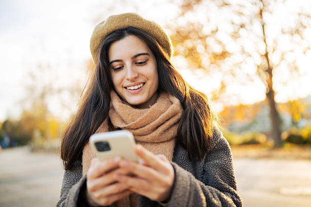istock Happy Young Woman Texting on Her Phone Surrounded by Fall Foliage 2247459105