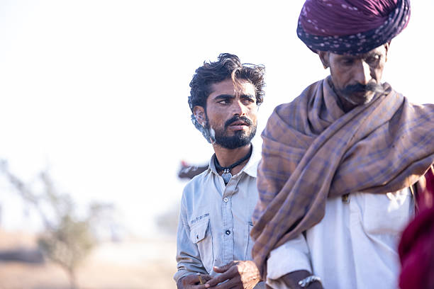 Pushkar, Rajasthan, India - November 2024: Portrait of a rajasthani male in traditional white clothes with colourful turban at desert fair ground during the pushkar camel fair to trade camels.