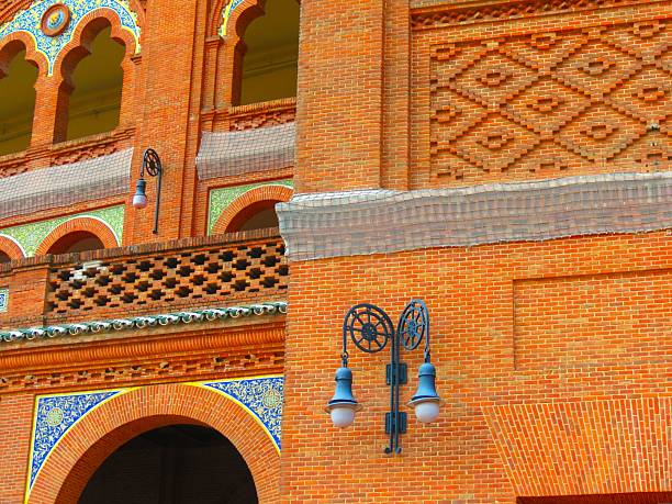 Closeup of exterior brick walls with pillars and arched windows, neo Mudejar style Las Ventas bullring, hanging lamps, sunny day in Madrid, Spain