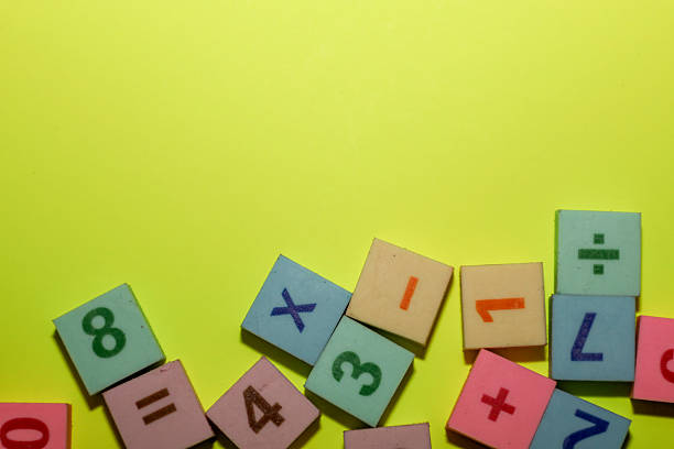istock A cluster of colorful educational blocks featuring numbers and mathematical symbols is arranged along the bottom edge against a vibrant yellow background. 2247461030