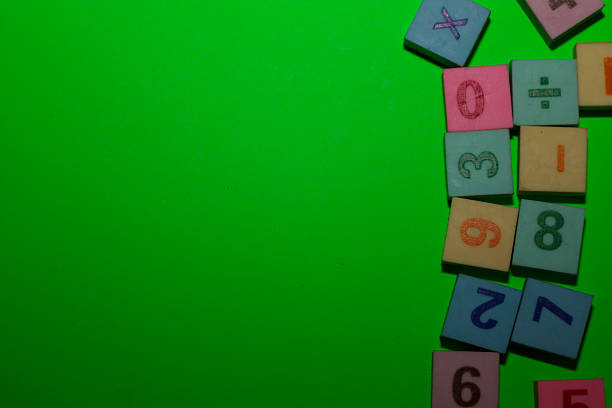 A cluster of colorful educational blocks featuring numbers and mathematical symbols is positioned in the top right and bottom right corners against a bright green background.