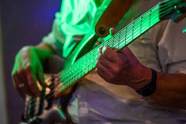 istock Guitarist plays bass guitar under vibrant green stage lighting during a live performance 2247462019