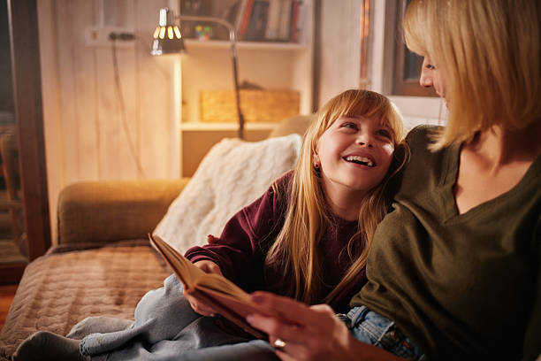 istock Mother and daughter reading book together at home 2247462957