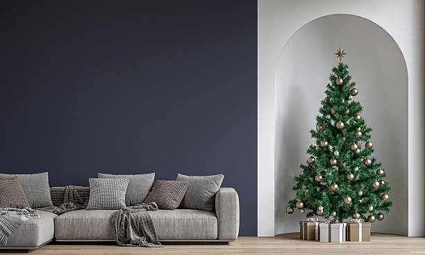 istock Modern minimalist interior decorated for Christmas, with sofa in front of dark blue plaster wall, a Christmas tree with presents in a wall niche, near a window 2247463292