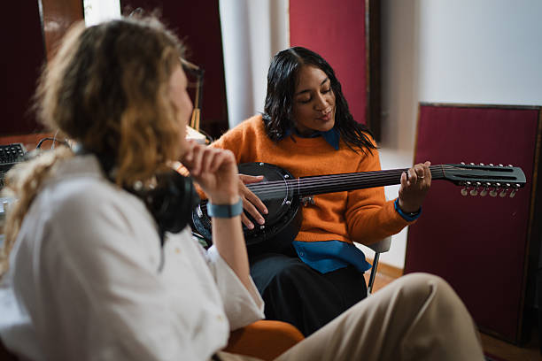 istock Two young women collaborating on music and playing banjo in studio 2247463526