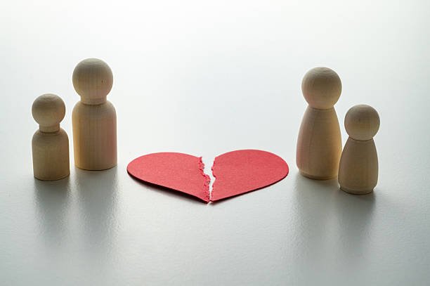 istock Divorce concept: torn red heart, tokens symbolizing husband and wife. 2247465211