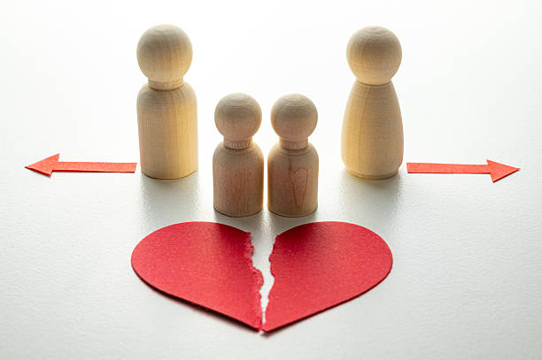 istock Divorce concept: torn red heart, tokens symbolizing husband and wife. 2247465241