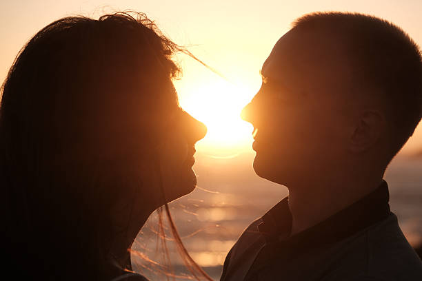 istock Silhouetted couple facing each other with the setting sun between them, creating a romantic and intimate golden hour moment 2247468379