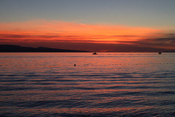 Seascape sunset over the sea, bright red sky, sun behind clouds on the horizon