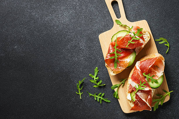 istock Open sandwiches with cream cheese, prosciutto, cucumber and arugula. 2247469096