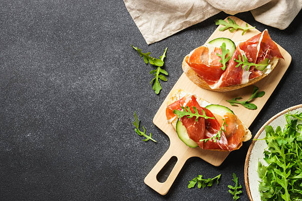 istock Open sandwiches with cream cheese, prosciutto, cucumber and arugula. 2247469097