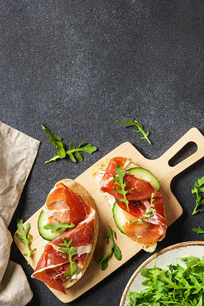 istock Open sandwiches with cream cheese, prosciutto, cucumber and arugula. 2247469184