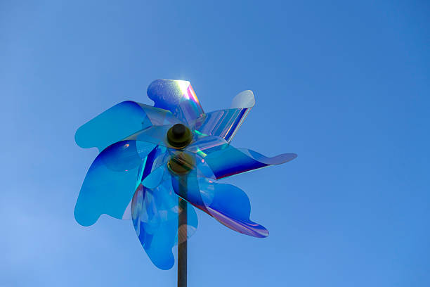 Brightly colored wind spinner spins gracefully against a clear blue sky on a sunny day, adding joy to the outdoor space, capturing the essence of a peaceful afternoon.