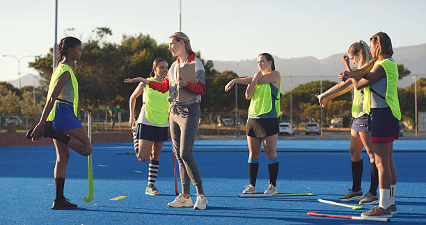 istock Women, hockey and players with coach, stretching and game plan with feedback, exercise and wellness. People, outdoor and instructor with athletes, workout and advice with practice, turf and fitness 2247473014