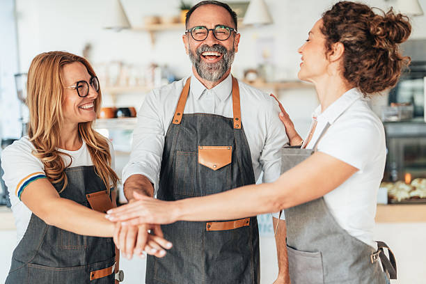 istock Happy coffee shop team with hands joining together 2247474114