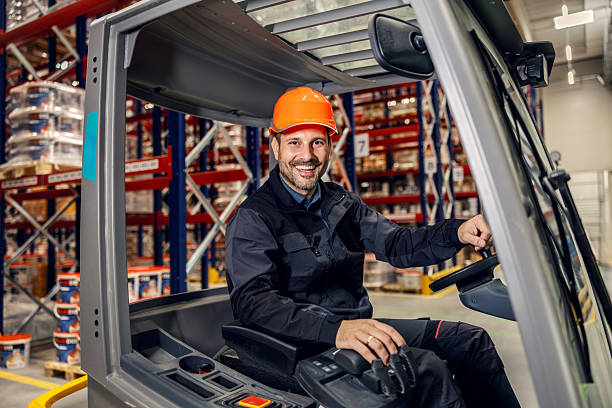 istock Smiling warehouse worker driving forklift in storage building 2247485299
