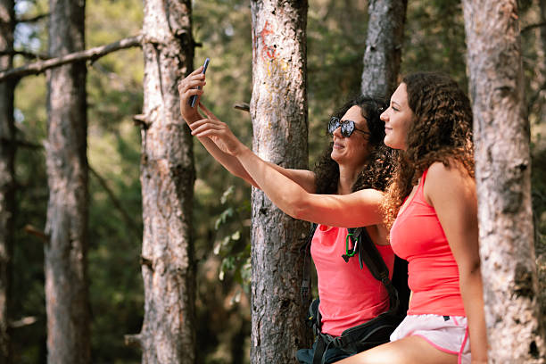 istock Friends enjoy a sunny day taking a selfie while relaxing in a forest surrounded by tall trees during a summer hike 2247485776