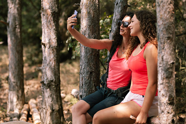 istock Friends enjoy a relaxing moment together in nature while taking selfies under the trees during a sunny afternoon 2247485797