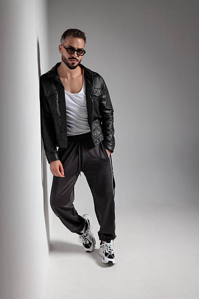 istock sexy young man leaning on a wall and holding hand in pocket 2247487027