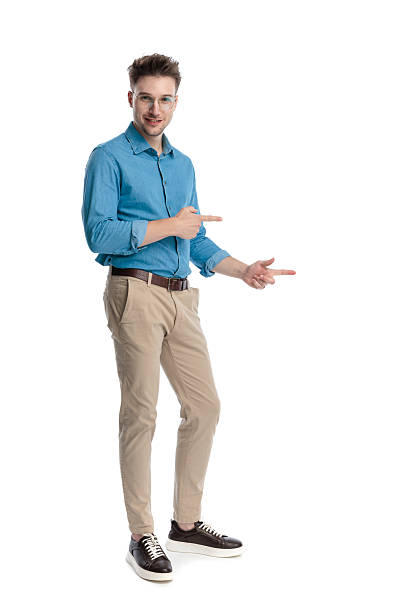 istock Happy casual man standing and pointing to side 2247488500