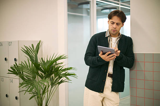 istock Young Adult Caucasian Man Reviewing Digital Documents on Tablet in Office 2247490501