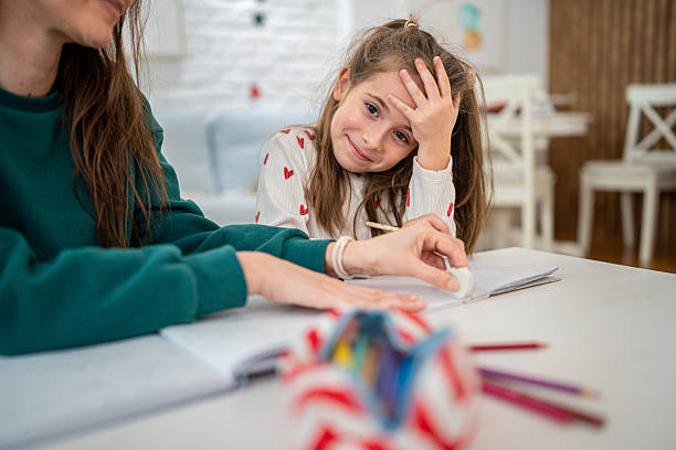 istock Mom Erasing Homework Mistake While Daughter Slaps Her Forehead, Both Sitting at the Living Room Table 2247490844