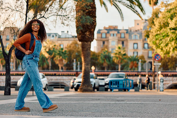 istock Smiling young woman walking through city street with backpack 2247494380