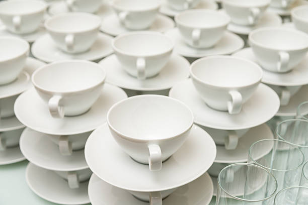 A neatly arranged collection of white porcelain tea cups and saucers. the minimalist design offers a sense of elegance, perfect for hospitality or event settings.