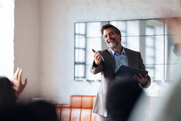 istock Confident Business Presenter Engages Group During Office Meeting With Friendly Gesture 2247507255