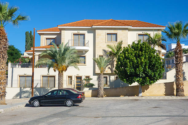 Kato Paphos, Cyprus – November 14, 2025: A residential building with palm trees is shown under a clear blue sky, photographed from the street with balconies, windows, and Mediterranean architectural details visible
